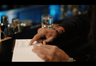 Bild zeigt eine Hand, die mit einem Finger auf eine Karte in einer Bar zeigt. Ausschnitt aus dem Werbespot zur Kirchenwahl am 1. Dezember 2019.