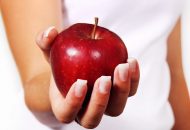 Fastenzeit: Das Bild zeigt einen weiblichen Arm und eine Hand, die einen roten Apfel hält.